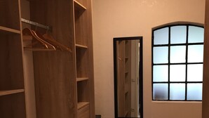 Garderobeskab med hylder i træ og en spejldør.