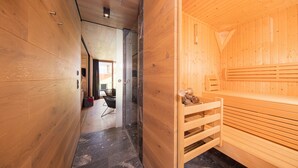 Interior de fusta amb zona de sauna, un bany modern i zona d'estar amb vistes.