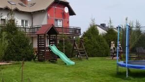 A residential property with a red and white house, a green slide, and a trampoline. - Family-friendly, green area, barbecue area, surrounded by pastures, nature park  (Rowy)