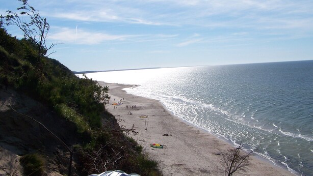 A beach with a clear sky, sandy shore, and a few people. - Family-friendly, green area, barbecue area, surrounded by pastures, nature park  (Rowy)