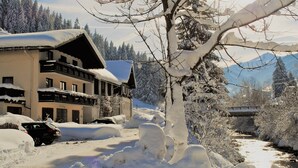 Un edificio cubierto de nieve con varios balcones y un paisaje montañoso al fondo.