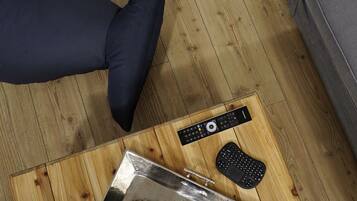 A wooden floor with a metal object, a black remote control, and a black keyboard.