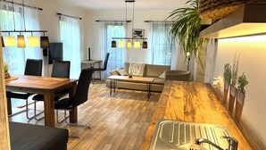 Una cocina moderna con encimera de madera, un lavamanos y una zona de comedor con mesa y sillas.