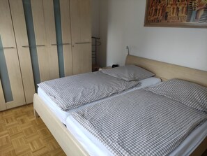 Makuuhuoneessa on kaksi sänkyä, puinen vaatekaappi ja seinällä taulu.