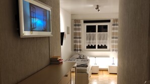 A modern bedroom with a bed, bedside tables, and a TV mounted on the wall.