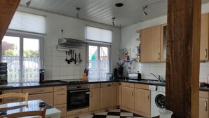 A kitchen with wooden cabinets, a black and white checkered floor, and a window with blinds.