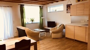 A cozy living room with a sofa, a TV, a small table, and a window with curtains. - Holiday tower Niederstetten (Niederstetten)