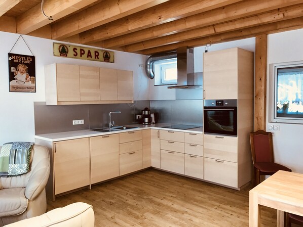 A modern kitchen with wooden cabinets, a stainless steel sink, and a built-in oven.