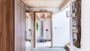 A hallway with wooden flooring, a wooden door, and a wall-mounted photo collage.