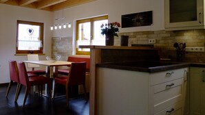 Una cocina con vigas de madera, un comedor con sillas rojas y un microondas sobre la encimera.