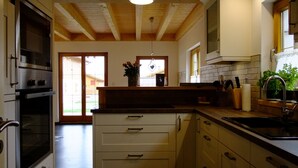 Una cocina moderna con vigas de madera, horno de acero inoxidable y un ventanal grande.