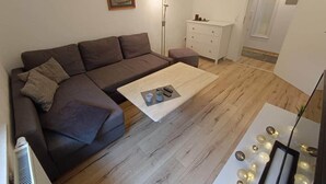 Un salon avec un canapé marron, une table basse blanche et un meuble blanc.