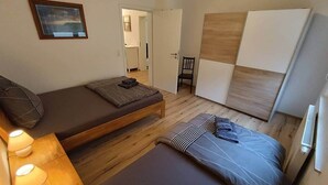 Une chambre à coucher de taille réduite, comprenant un lit, une chaise et une petite table avec des lampes.