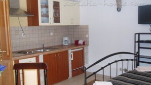 Quarto compacto com cama, cozinha compacta e banheiro.