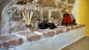Paredede pedra com uma prateleira exibindo incenso, pinhas e um lanterna vermelha.