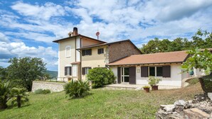A two-story house with a stone facade and a tiled roof, surrounded by a grassy yard and trees. - Panorama-Ferien-Toscana
Your vacation home in Tuscany (massa marittima)