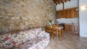 A stone-walled kitchen with wooden cabinets, a dining table with chairs, and a floral sofa. - Panorama-Ferien-Toscana
Your vacation home in Tuscany (massa marittima)