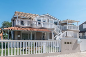 A two-story house with a balcony, a covered patio, and a gated entrance.