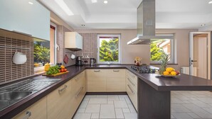Een moderne keuken met een centraal eiland, inbouwapparatuur en uitzicht op groen.