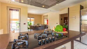 Een moderne keuken met een centraal eiland, roestvrijstalen apparatuur en een eethoek op de achtergrond.