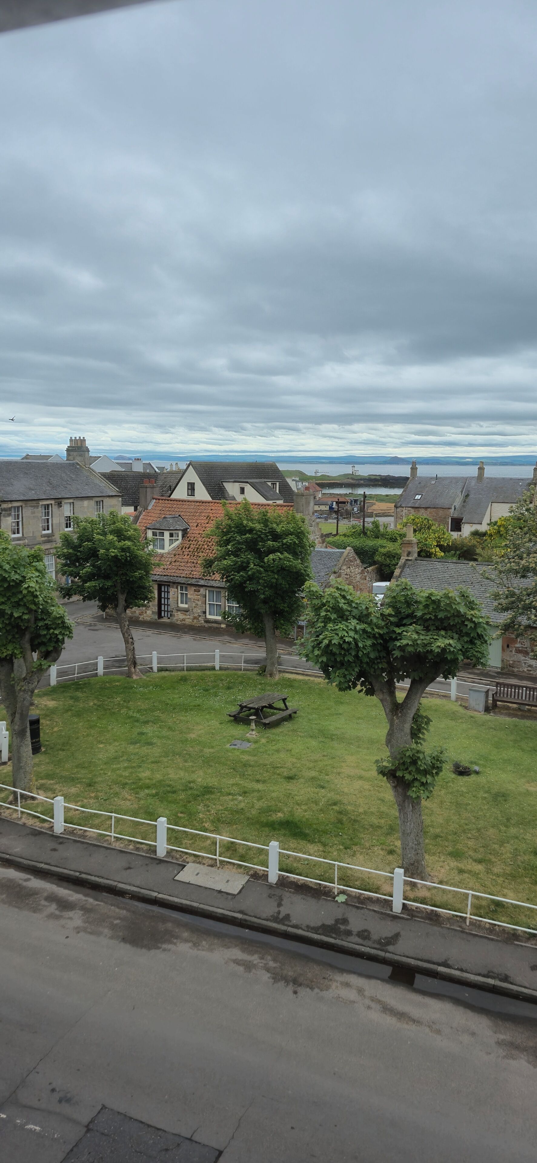 Un barrio residencial con casas, un parque con césped y vistas al mar.
