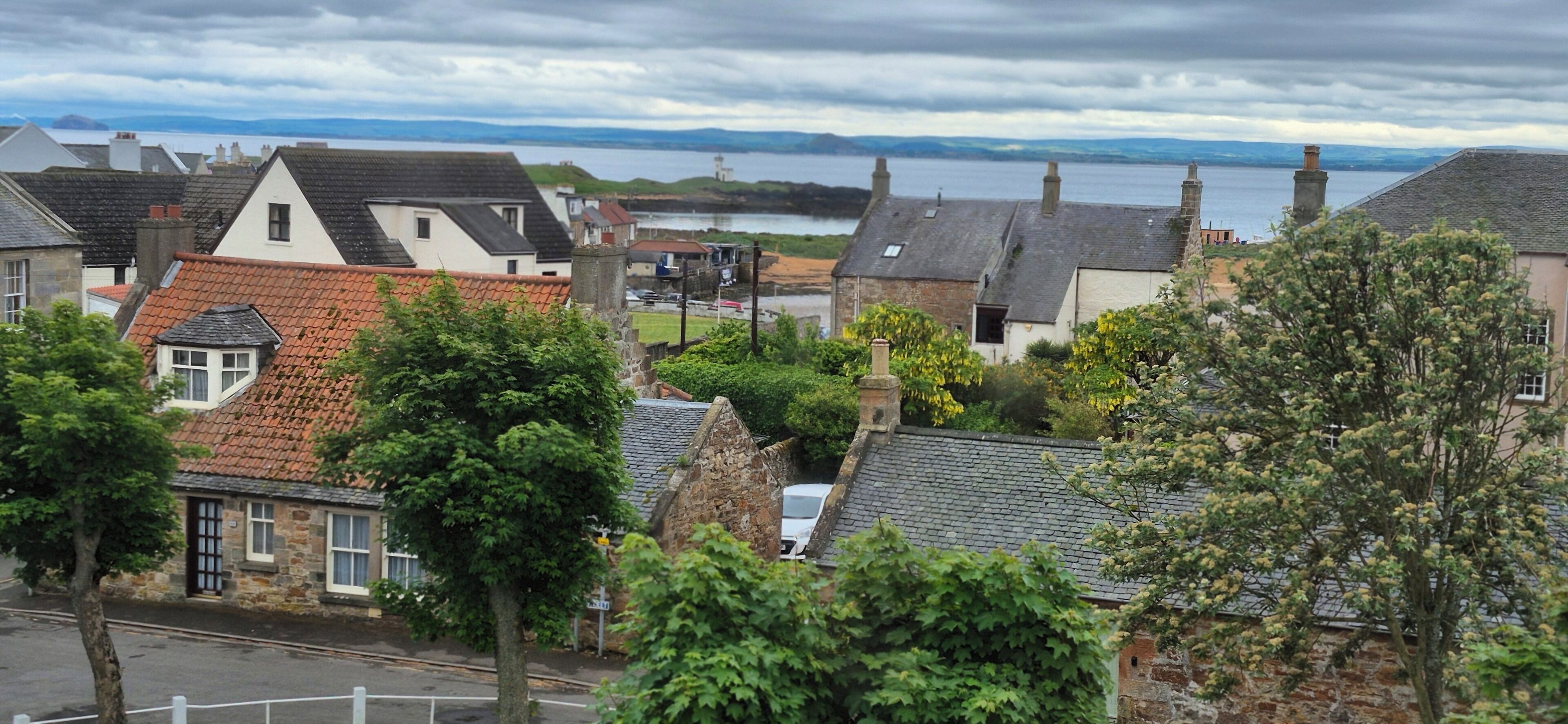 Une ville côtière avec des bâtiments en pierre, une vue sur la mer et un ciel nuageux.