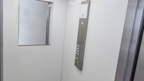 A modern elevator with a control panel and a mirror on the wall.