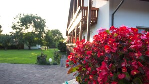 A house with a wooden balcony and a garden with red flowers. - Arrive, switch off ... feel good (Aidenbach)
