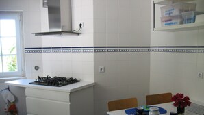 Eine Küche mit Gasherd, weißen Schränken und einem Fenster.
