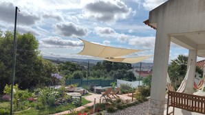 Ein Garten mit Terrasse, einer Hängematte und Blick auf die Landschaft.