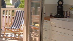 Een kamer met een houten terras, een streepjesstoel, een koffiezetapparaat en een keukenwerkblad.