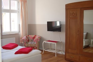 A bedroom with a bed, a chair, a TV, and a wardrobe.