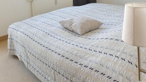 A bedroom with a large bed, a window with curtains, a framed picture on the wall, and a bedside lamp. - Close to the beach, comfortable apartment in a very good location! (Kühlungsborn Ost)