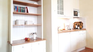 A kitchen with white cabinets, a wooden countertop, and a microwave above the sink. - Close to the beach, comfortable apartment in a very good location! (Kühlungsborn Ost)