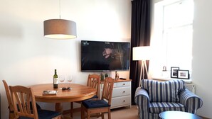 A living room with a dining area, a sofa, a TV, and a lamp. - Close to the beach, comfortable apartment in a very good location! (Kühlungsborn Ost)