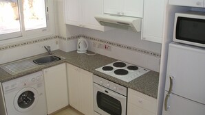 A compact kitchen with a built-in washer, a stove, and a microwave.
