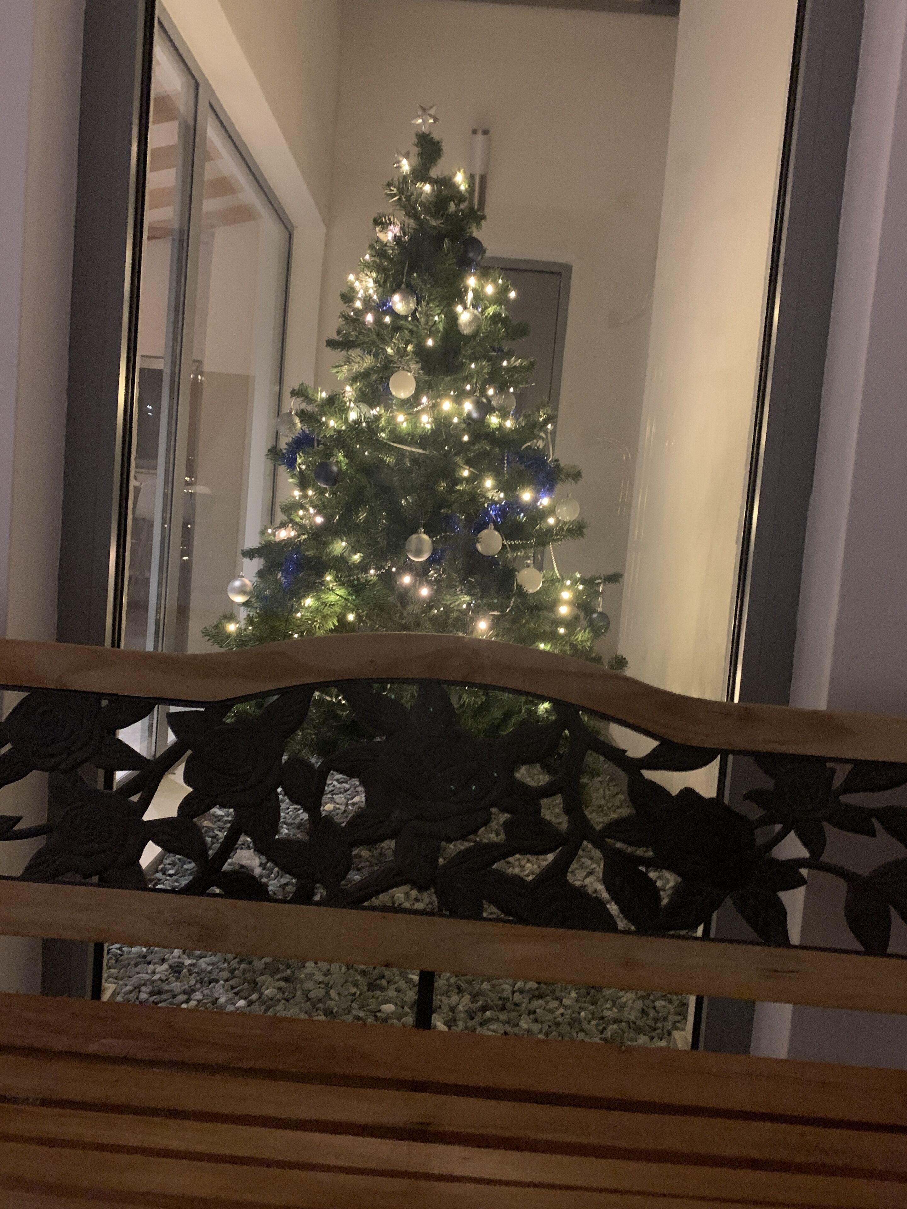 A Christmas tree with lights and ornaments in a hallway.