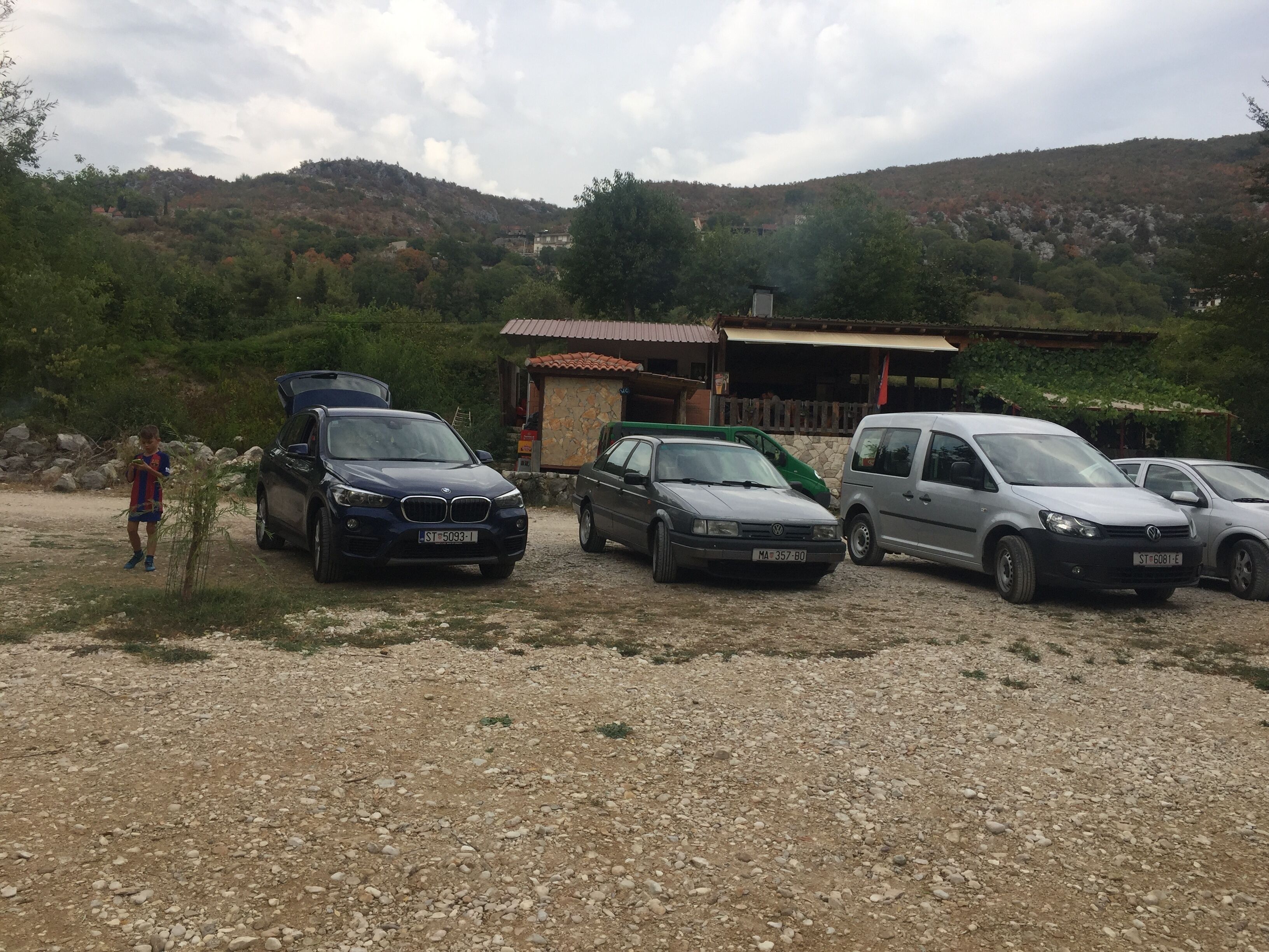 A gravel parking area with several cars parked.
