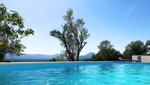 A clear blue swimming pool with a view of mountains in the background.