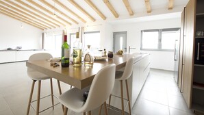 A modern kitchen with wooden beams, a central island with chairs, and a refrigerator.