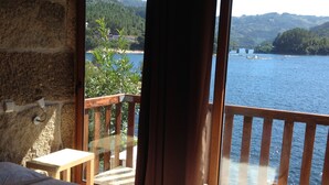 Un dormitorio con un ventanal grande que da a un lago y colinas.