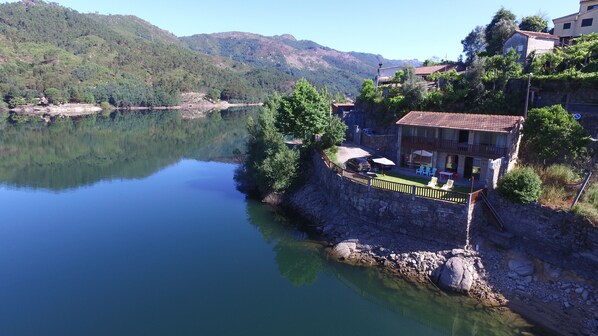A lakeside property with a stone wall, outdoor seating, and a view of the lake and surrounding hills. - Geres - Vacation / Weekends (Gerês)