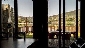 Una terraza con vista a un lago y colinas, un edificio de piedra y una zona de barbacoa.