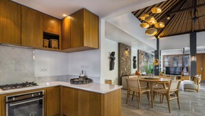 A modern kitchen with wooden cabinets, a marble countertop, and a built-in oven. There is a dining area with a wooden table and chairs.