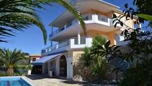 A multi-story building with balconies, a swimming pool, and surrounding greenery. - Villa Orea Thea with pool, German standard for up to 6 people (Syvota)