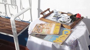 Une table avec un magazine, un plateau avec des tasses et des soucoupes, et une chaise en bois.