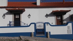 Un bâtiment avec un toit recouvert de tuiles rouges, des murs blancs et des éléments décoratifs bleus.