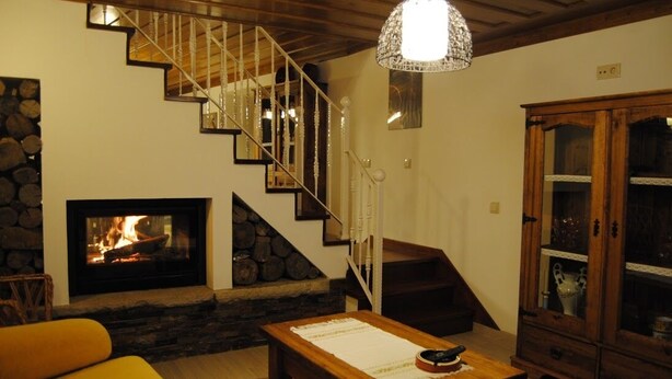 Un salon chaleureux avec une cheminée, un escalier en bois, une table à manger et un buffet.