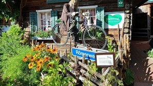 A rustic wooden building with a bicycle mounted on a wooden structure in front.