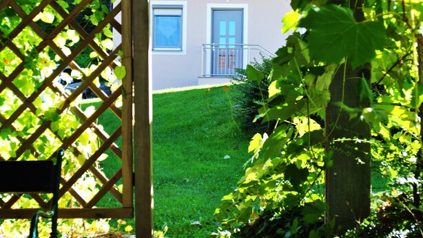A residential building with a well-maintained lawn, a wooden lattice gate, and a balcony.